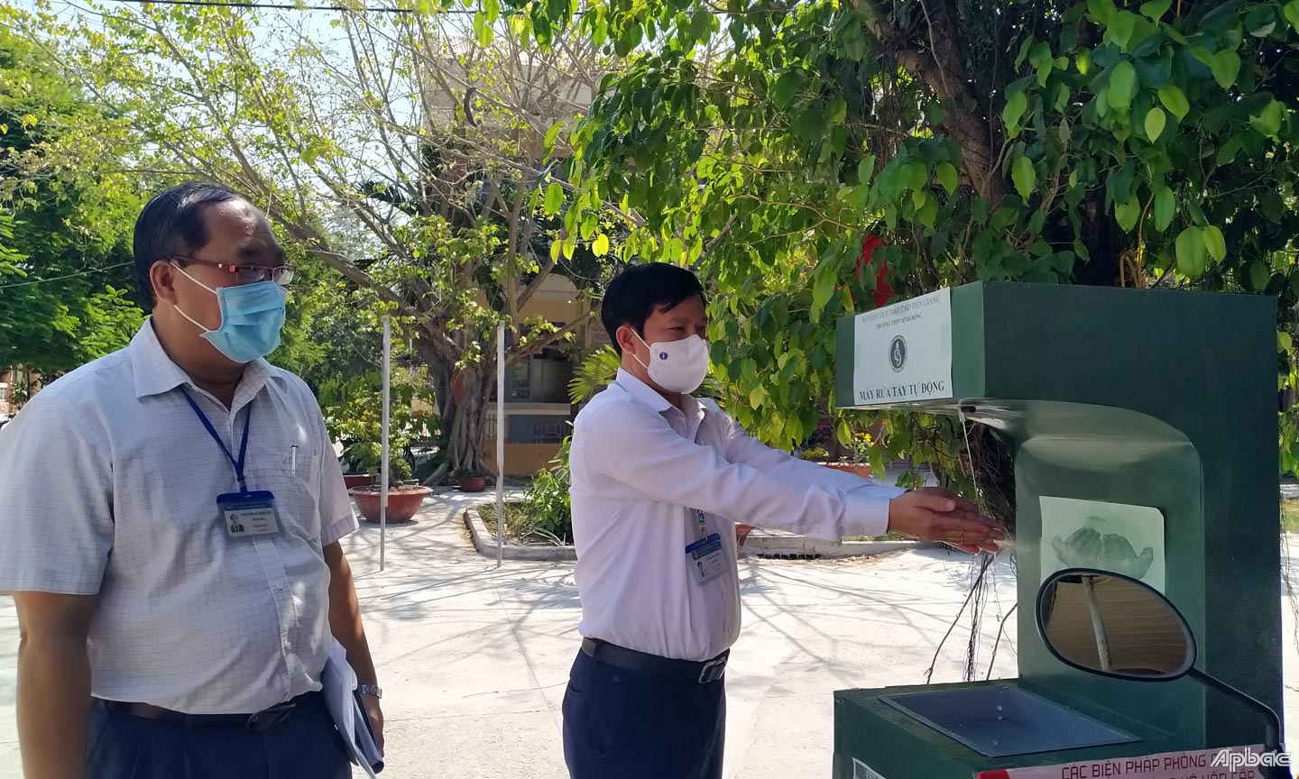 Đồng chí Lê Quang Trí kiểm tra hệ thống máy rửa tay sát khuẩn do nhóm học sinh Trường THPT Bình Đông thực hiện. 