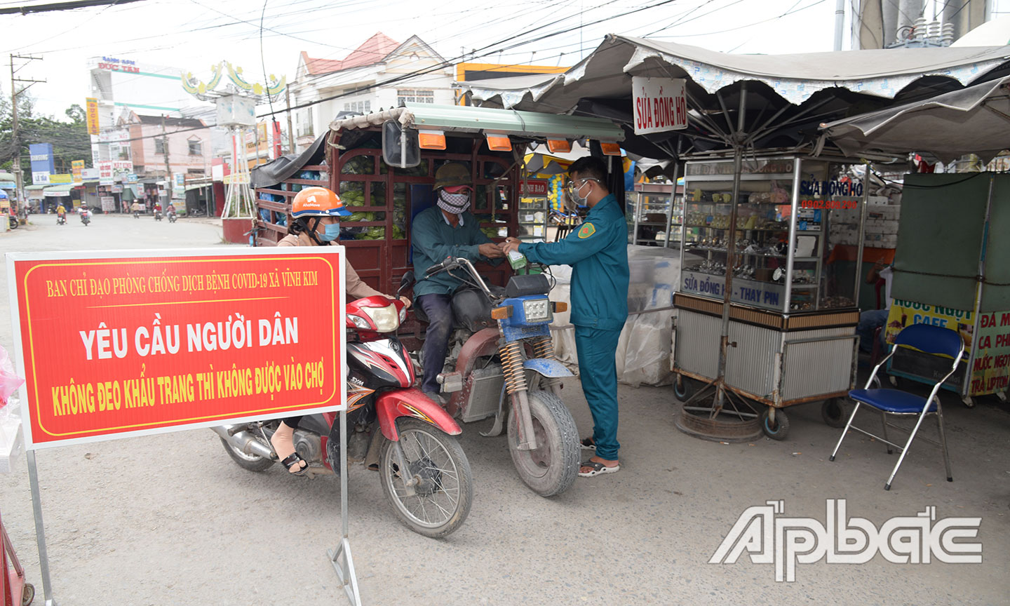 Chốt kiểm soát y tế đo thân nhiệt và sát khuẩn tay cho người dân trước khi vào chợ Vĩnh Kim.