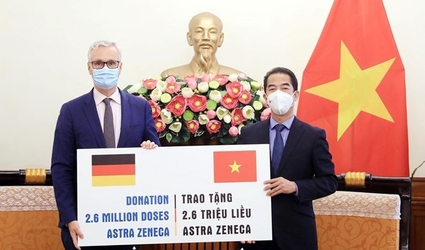  Deputy Minister of Foreign Affairs To Anh Dung (R) receives a token of the vaccine from German Ambassador to Vietnam Guido Hildner at the ceremony. (Photo: VNA).