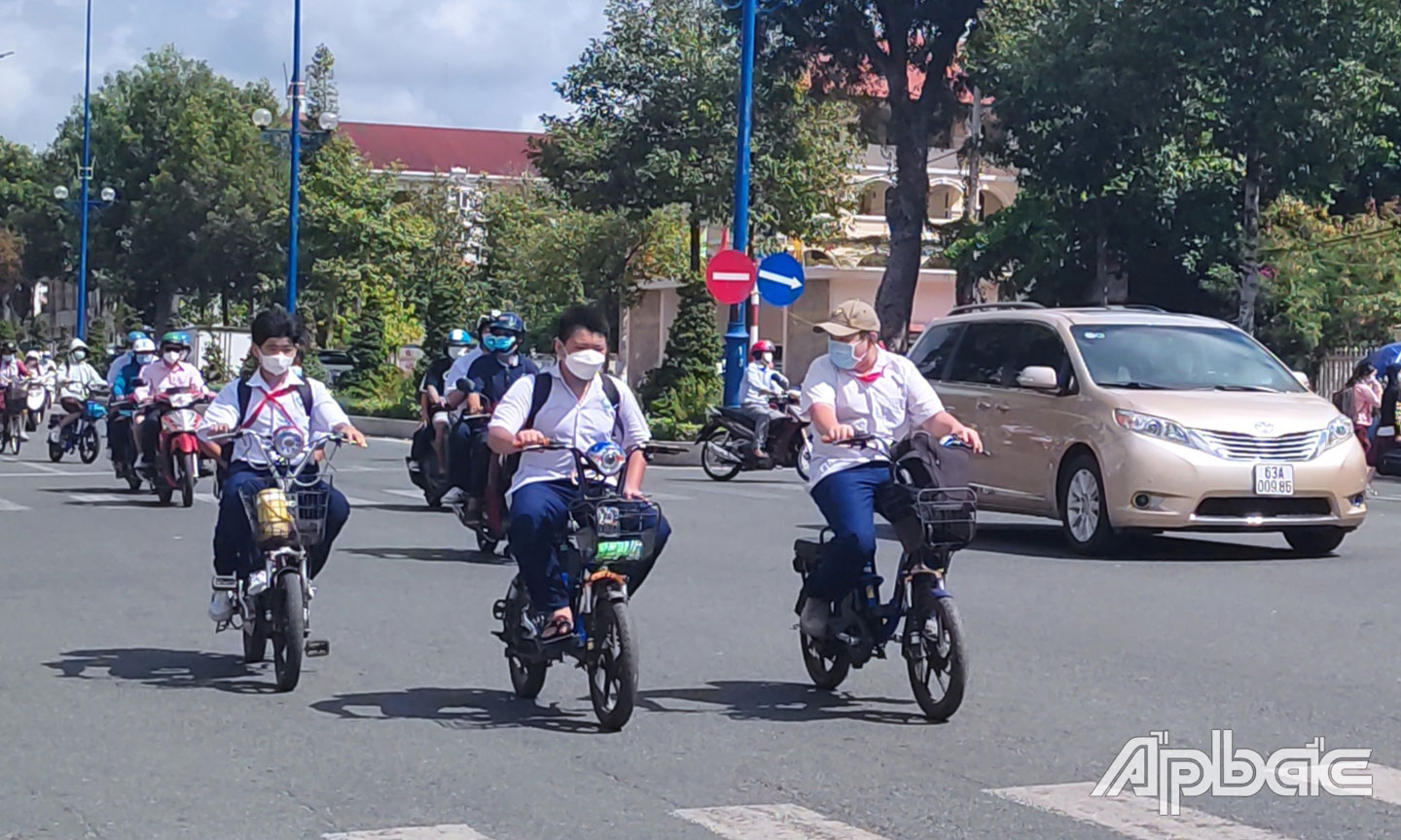 Học sinh không đội nón bảo hiểm khi đi xe đạp điện và đi hàng 3 trên đường Hùng Vương (TP. Mỹ Tho). 