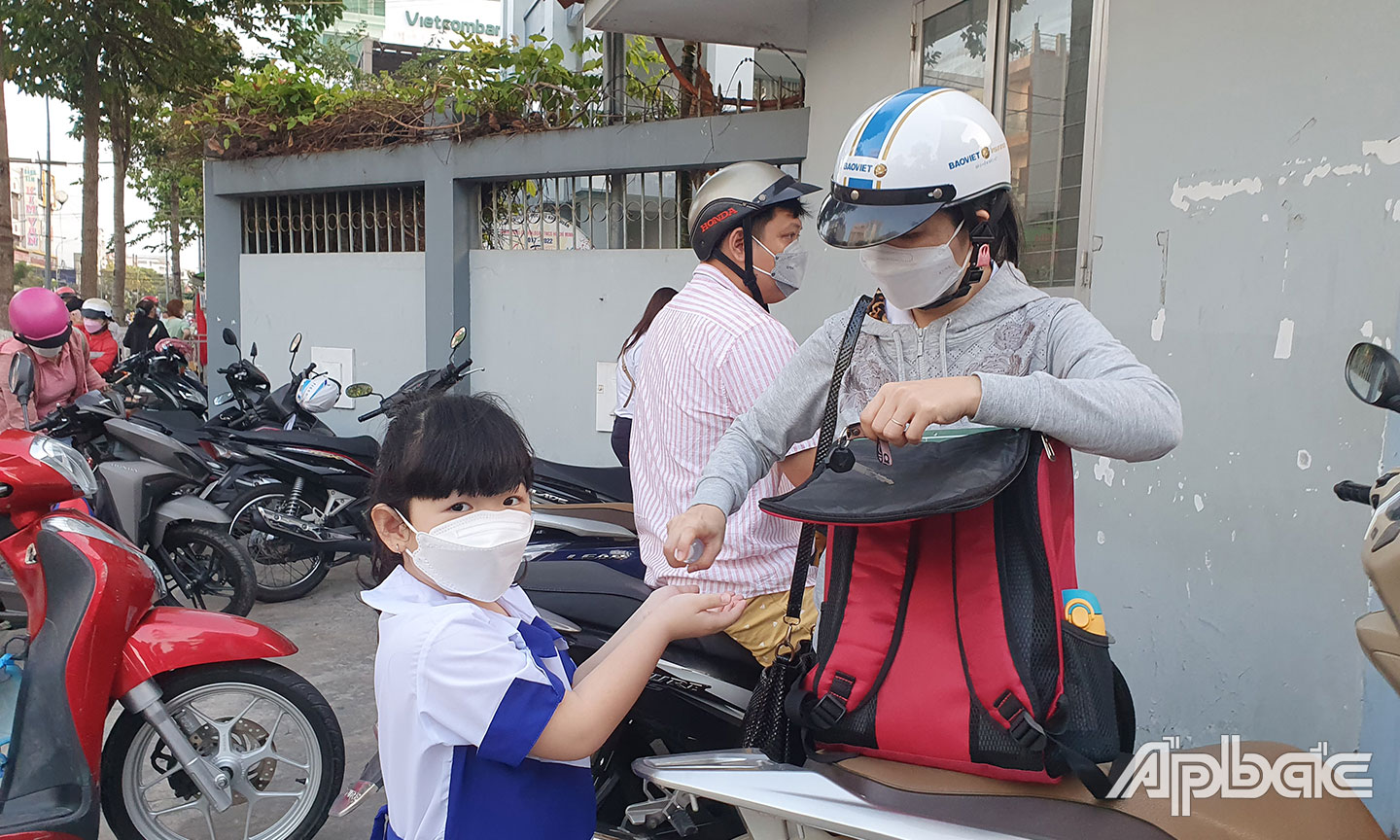 Để học sinh đến trường an toàn, rất cần sự phối hợp chặt chẽ của phụ huynh với nhà trường.  Ảnh chụp học sinh Trường Tiểu học Thủ Khoa Huân, TP. Mỹ Tho được phụ huynh rửa tay sát khuẩn  trước khi vào trường. 