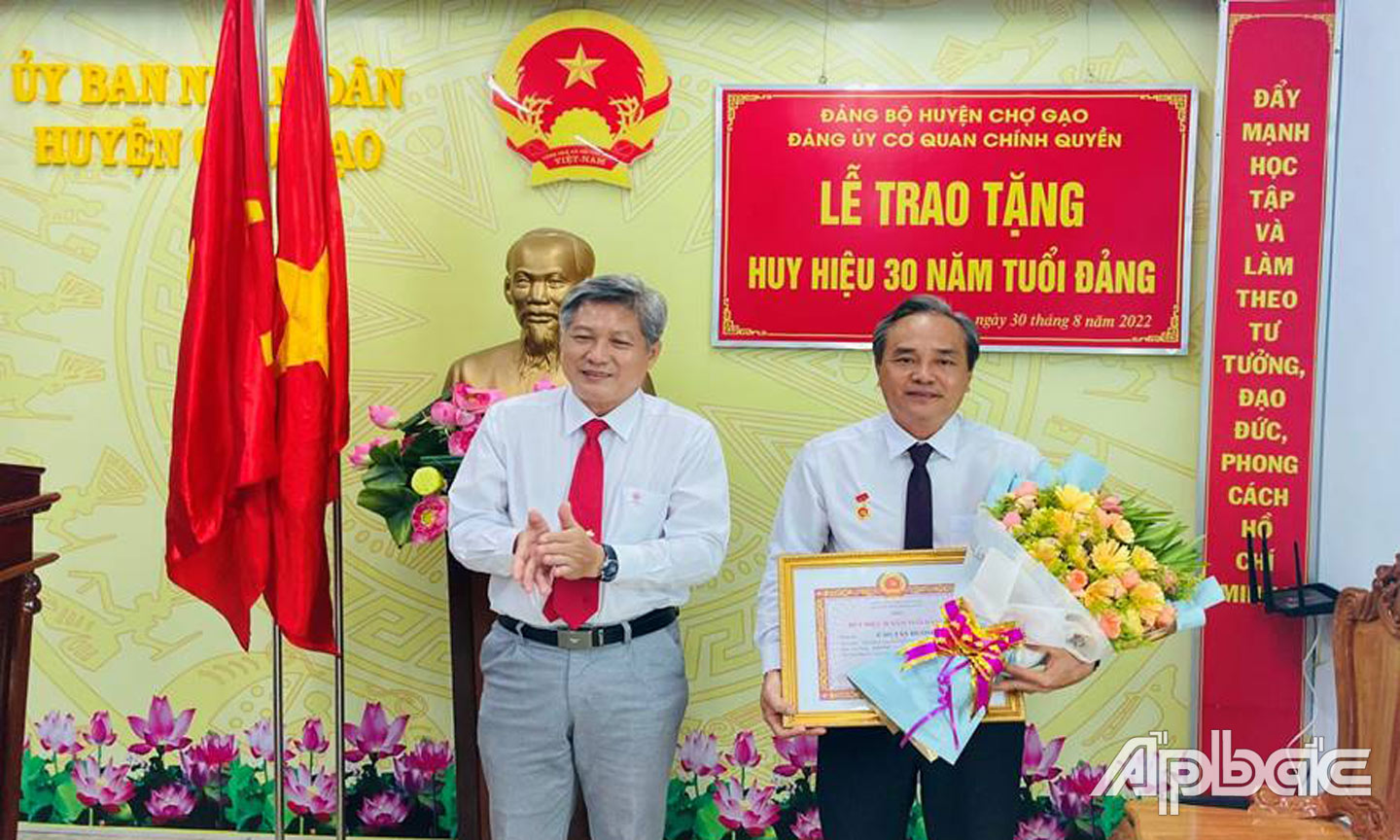 Ông Nguyễn Hồng Hữu, Tỉnh ủy viên, Phó Bí thư Huyện ủy, Chủ tịch UBND huyện Chợ Gạo trao Huy hiệu 30 năm tuổi Đảng cho đồng chí Cao Tấn Hưởng.