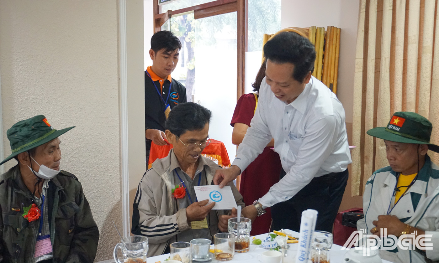 Phó Chủ tịch UBND tỉnh Nguyễn Thành Diệu cài hoa và tặng quà cho người có công trước khi tham quan thủ đô Hà Nội. 