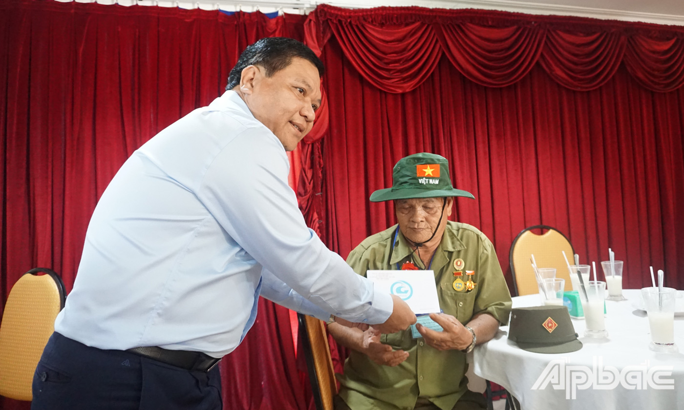 Giám đốc Sở Lao động - Thương binh và Xã Hội tỉnh Lý Văn Cẩm cài hoa và và tặng quà cho người có công trước khi tham quan thủ đô Hà Nội. 
