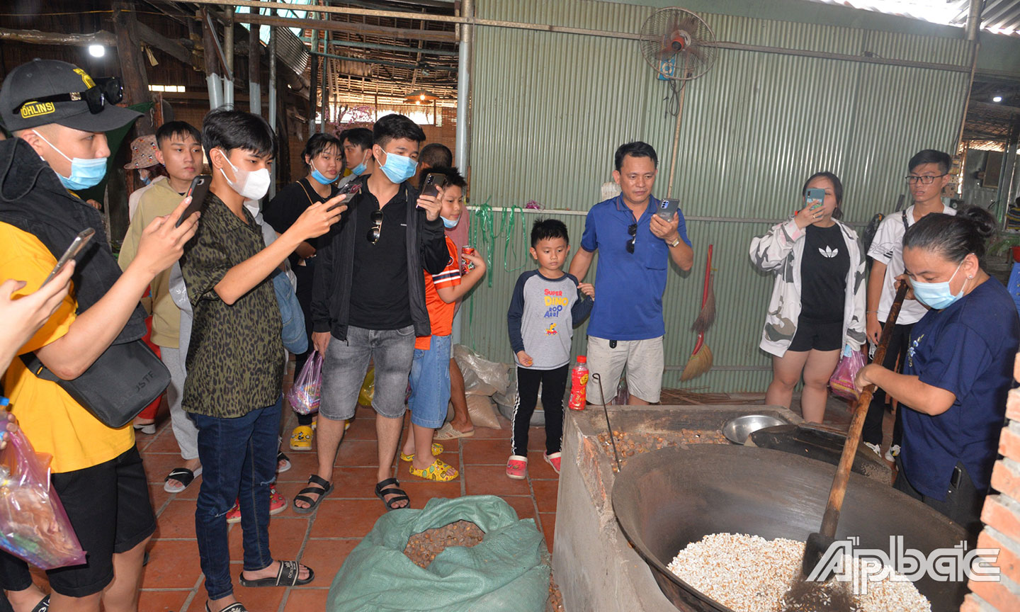 Khách tham quan trải nghiệm quy trình làm cốm ở Làng nghề cốm An Ninh, xã Đông Hòa Hiệp.
