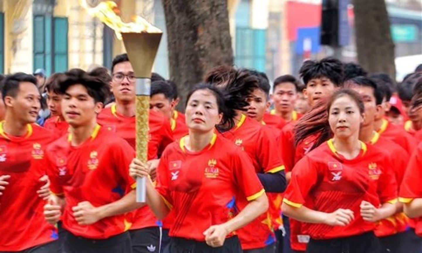 Vietnamese runner Nguyen Thi Huyen, who is multi-time SEA Games winner, and outstanding Vietnamese athletes carry the torch around the Hoan Kiem Lake area. (Photo: VNA).