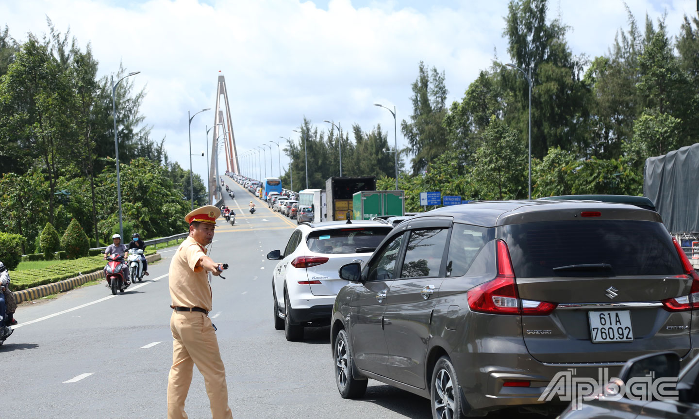 Lực lượng CSGT nỗ lực điều tiết phương tiện lưu thông qua cầu Rạch Miễu.