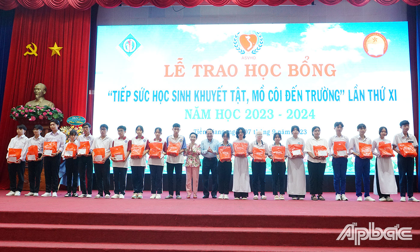 Đồng chí Trương Thị Hiền và đồng chí Phạm Văn Trọng trao học bổng và quà cho các học sinh khuyết tật, mồ côi. 