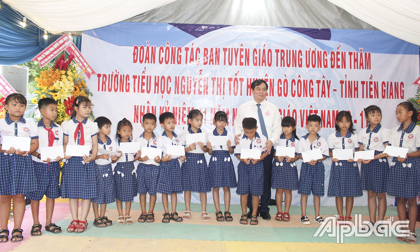 Phó Trưởng ban Tuyên giáo Trung ương Phan Xuân Thủy trao quà cho các em học sinh.