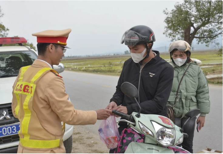 Lực lượng Cảnh sát Giao thông Công an tỉnh Điện Biên phát quà cho người dân trên đường về quê ăn Tết năm 2023. (Ảnh: Xuân Tư/TTXVN)