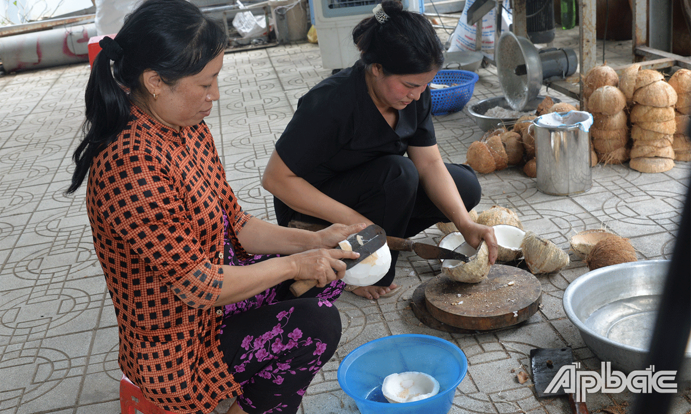 Chị Lắm (áo đen) chuẩn bị nguyên liệu làm mứt dừa.