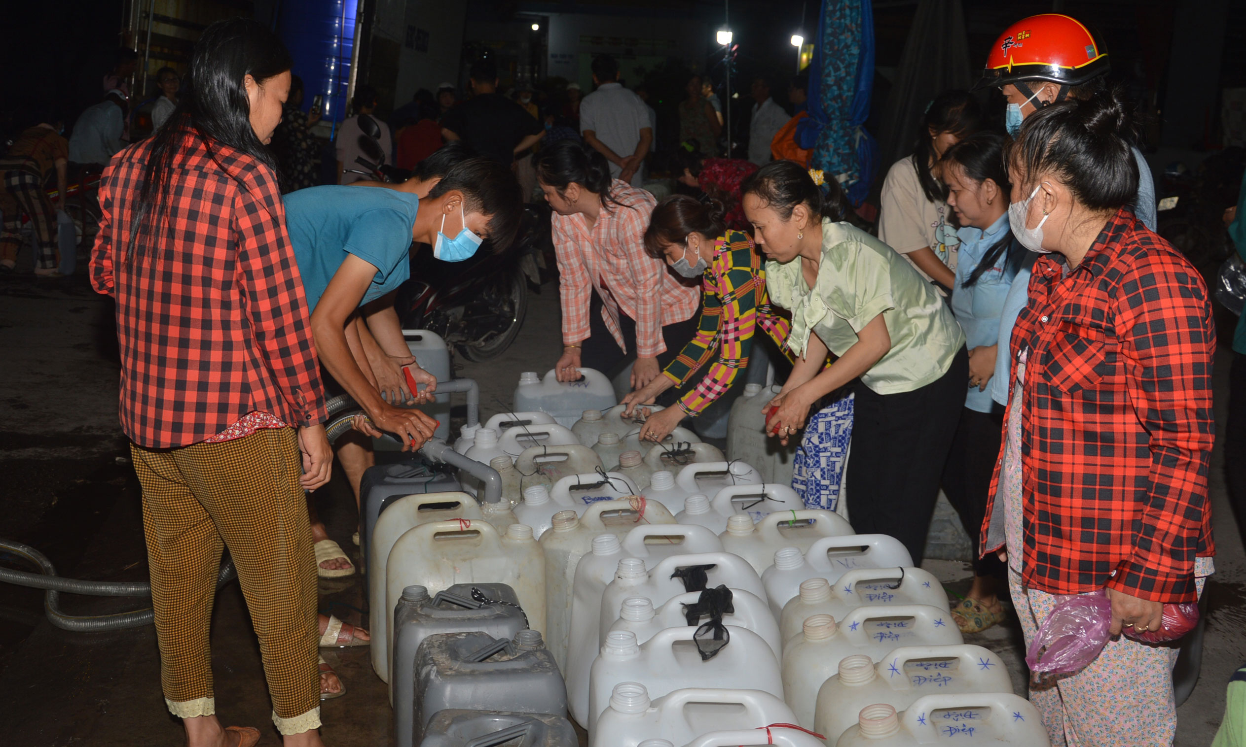 ​ Hàng trăm người dân ở ấp 2, xã Tân Phước, huyện Gò Công Đông mang can nhựa đến lấy nước từ các xe chở nước từ thiện trong đêm tối.