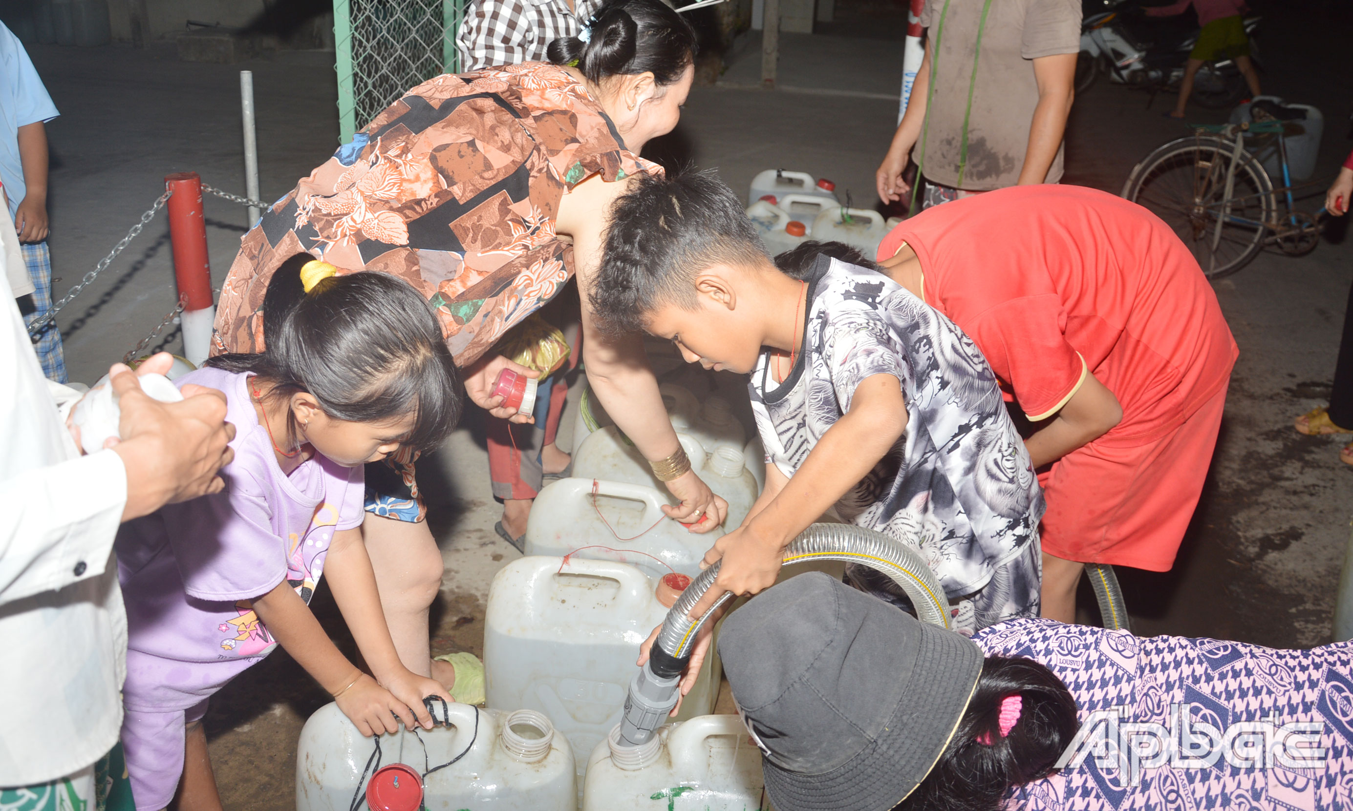 Hơn 20 giờ đêm, các em nhỏ ở xã Tân Phước cũng túc trực phụ cha mẹ lấy nước sinh hoạt vào can nhựa để mang về sử dụng.