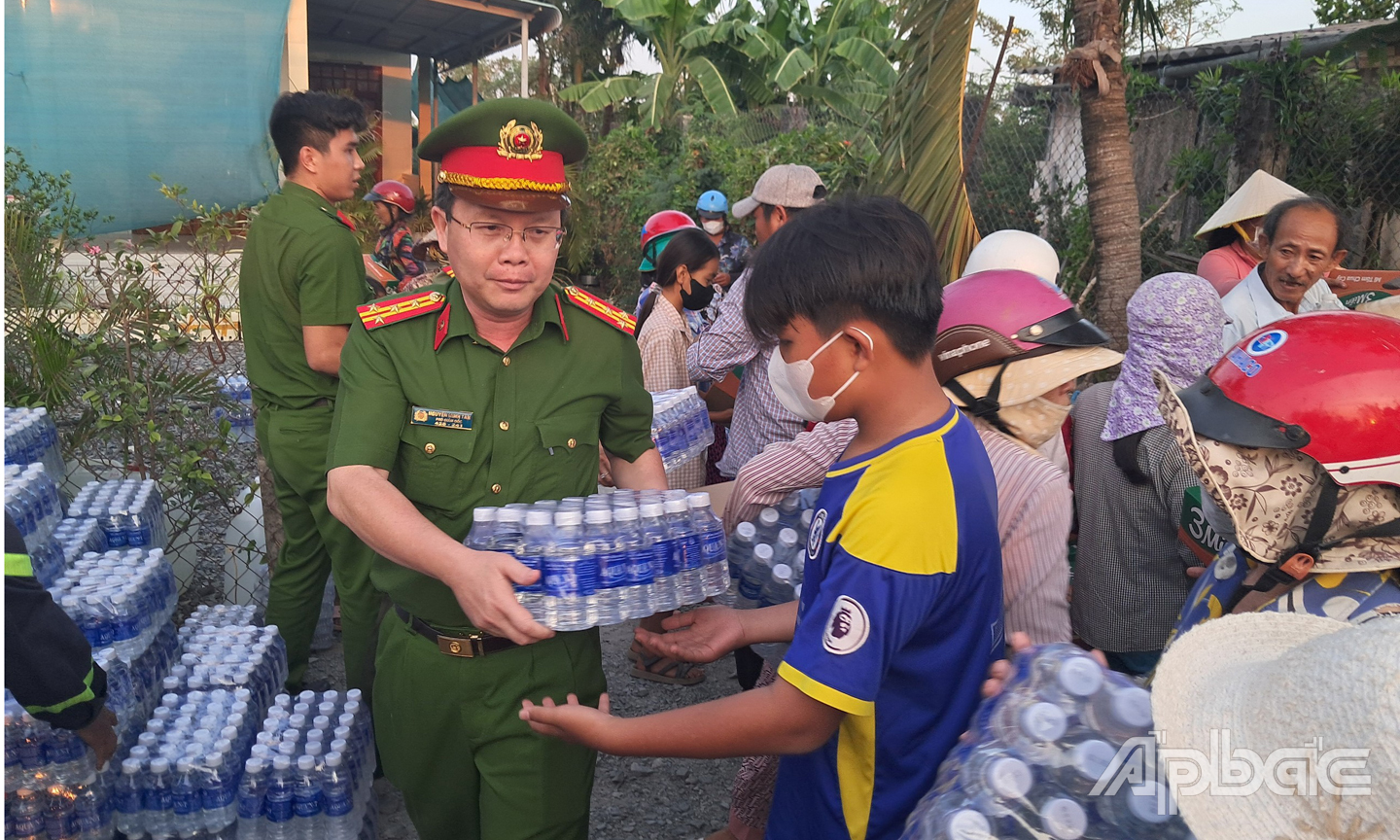 Đại tá Nguyễn Minh Tân, Phó giám đốc Công an tỉnh Tiền Giang tham gia chương trình  và trực tiếp phát nước cho người dân tại xã Kiểng Phước, huyện Gò Công Đông. Ảnh: Lê Hoài