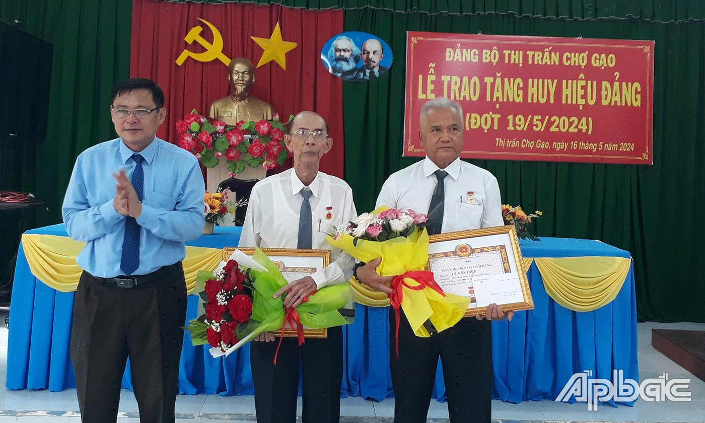 Đồng chí Đỗ Tấn Hùng trao huy hiệu Đảng cho 2 đảng viên tại Thị trấn Chợ Gạo.