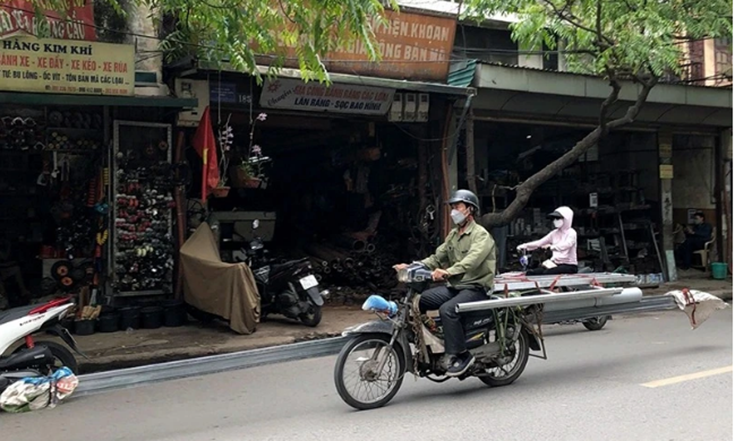 Xe máy cũ, nát chở hàng cồng kềnh trên phố Đê La Thành (Hà Nội). (Ảnh HỮU NGHỊ)