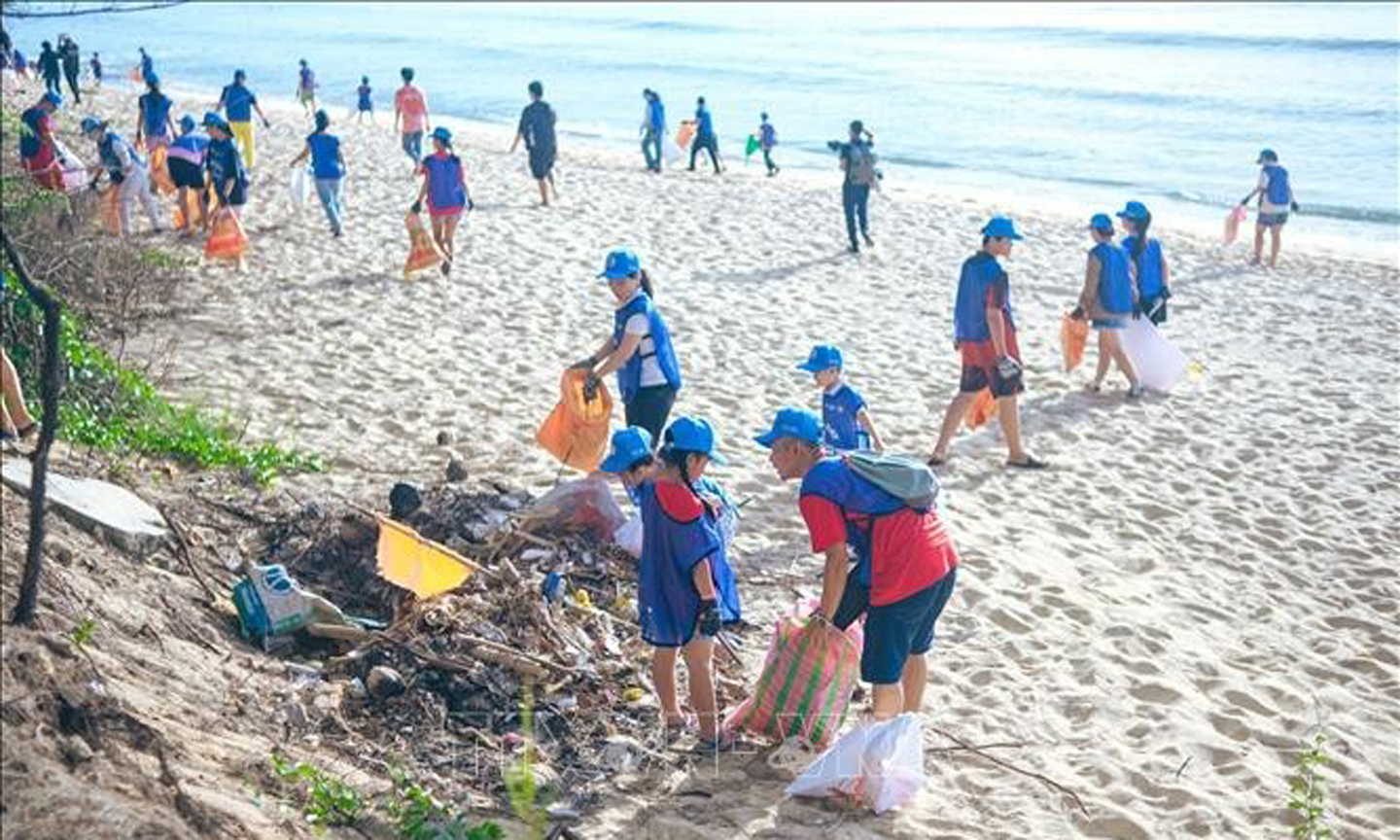 Youths and children clean up a beach (Photo: VNA).