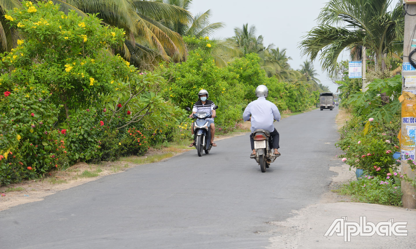 Người dân di chuyển trên một tuyến đường được phủ xanh hoa và cây cảnh ở xã Tân Hòa Thành.