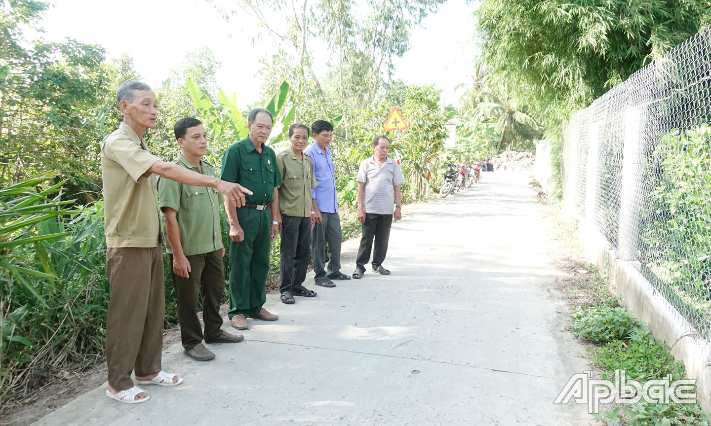 Cựu chiến binh Nguyễn Văn Mười (bìa trái) trao đổi với cán bộ, hội viên cựu chiến binh xã Mỹ Thành Nam ở tuyến đường Đập Đìa Dứa do ông hiến đất xây dựng.