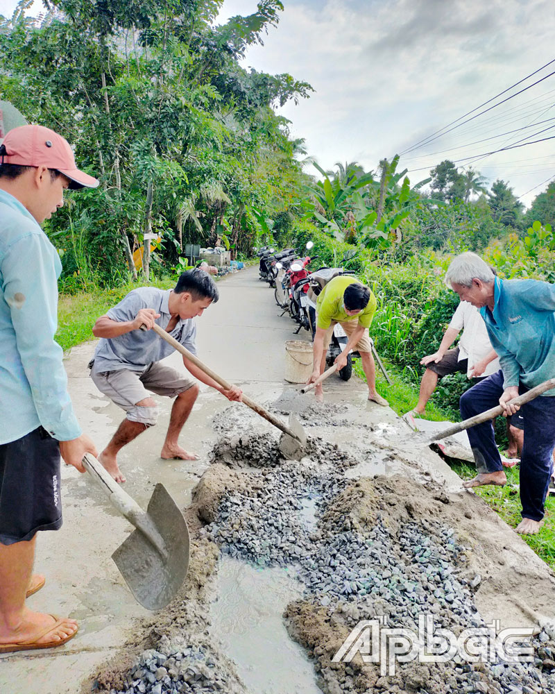 Người dân chung tay dặm vá đường, góp phần chung tay xây dựng NTM. 