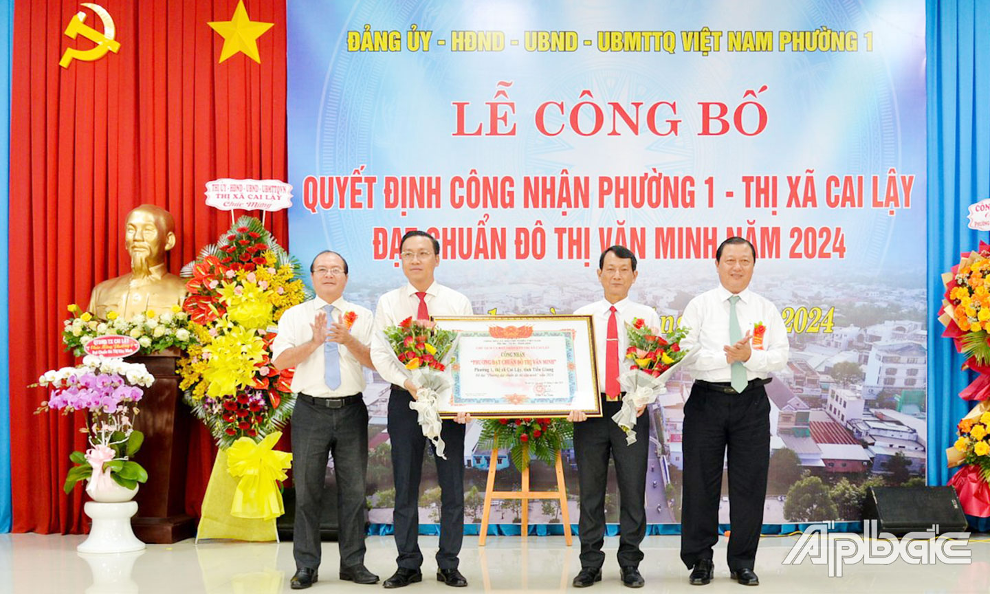 Đồng chí Phan Phùng Phú, Ủy viên Ban Thường vụ Tỉnh ủy, Bí thư Thị ủy, Chủ tịch HĐND TX. Cai Lậy và đồng chí Trần Văn Thức,  Chủ tịch UBND TX. Cai Lậy trao Quyết định công nhận “Phường đạt chuẩn đô thị văn minh” và tặng hoa chúc mừng phường 1.