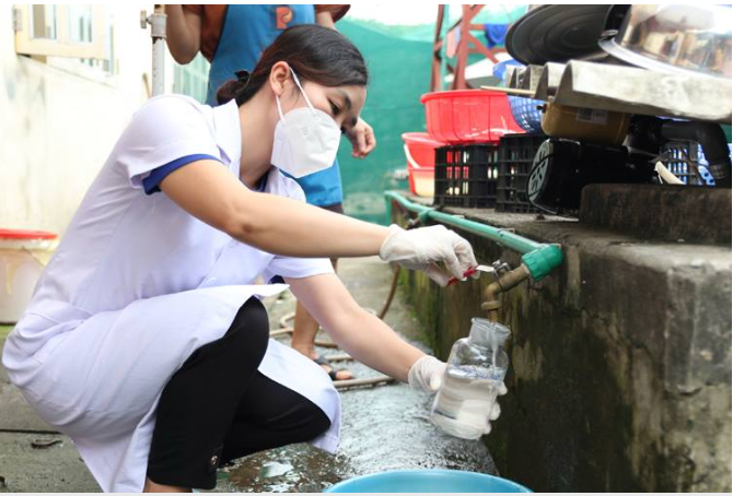 Cán bộ Trung tâm Kiểm soát bệnh tật Lào Cai lấy mẫu nước tại bể chứa nước bếp ăn số 1 của Trường Cao đẳng Lào Cai làm xét nghiệm. Ảnh: Lan Anh