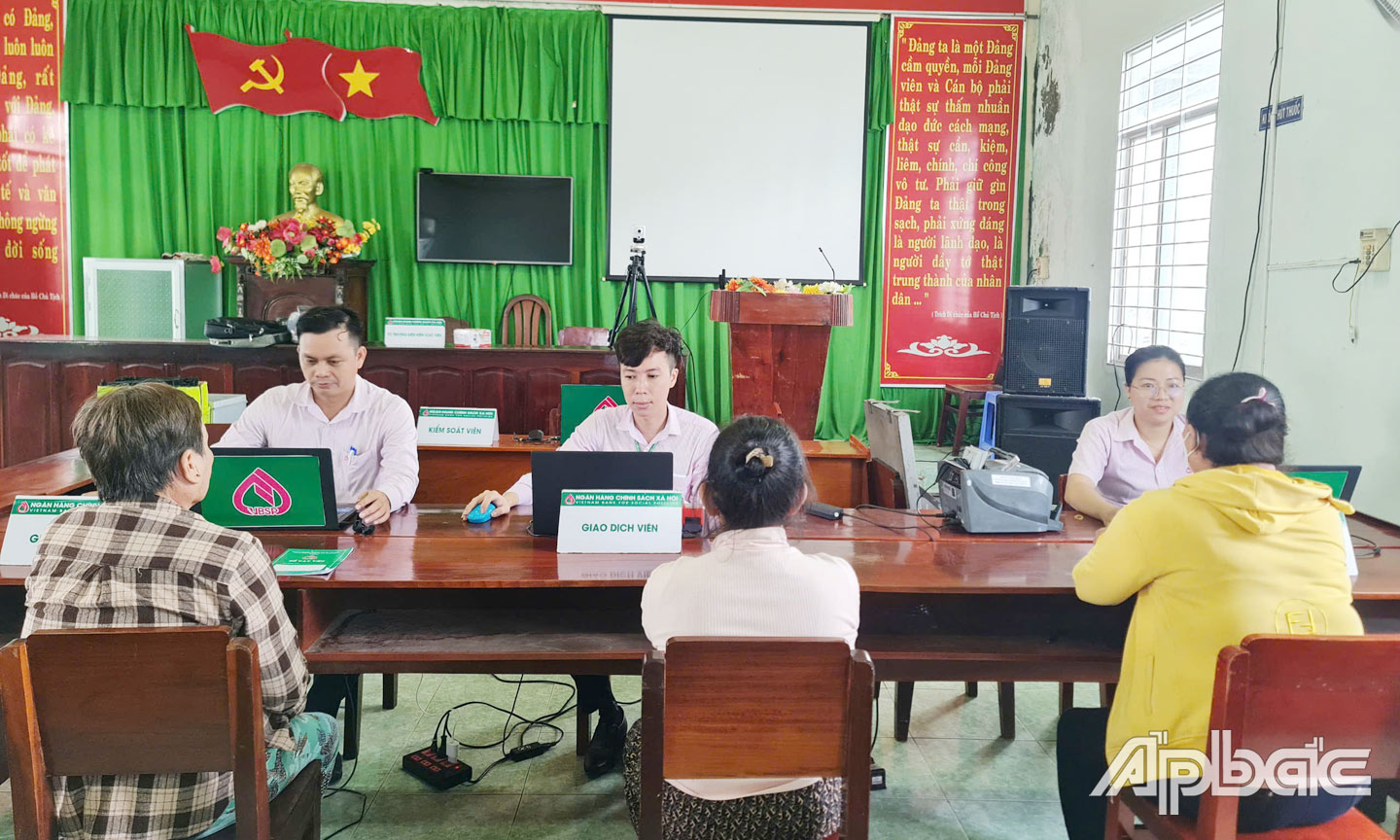 Nhân viên NHCSXH huyện hỗ trợ người dân giao dịch tại điểm giao dịch các xã trên địa bàn huyện.