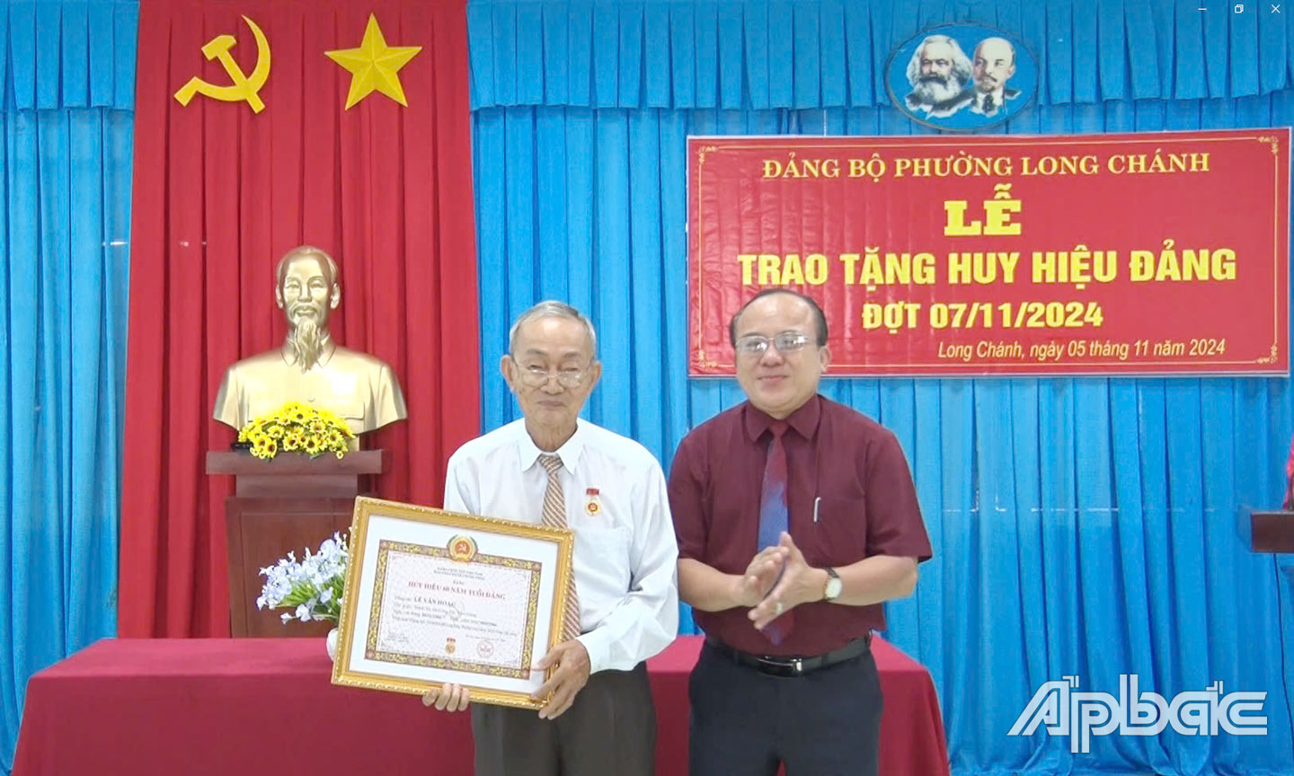 Đồng chí Nguyễn Chí Trung, Ủy viên Thường vụ Tỉnh ủy - Chủ tịch Ủy ban Mặt trận Tổ quốc Việt Nam tỉnh Tiền Giang, phụ trách Đảng bộ thành phố Gò Công tặng huy hiệu đảng cho Đồng chí Lê Văn Hoặc 