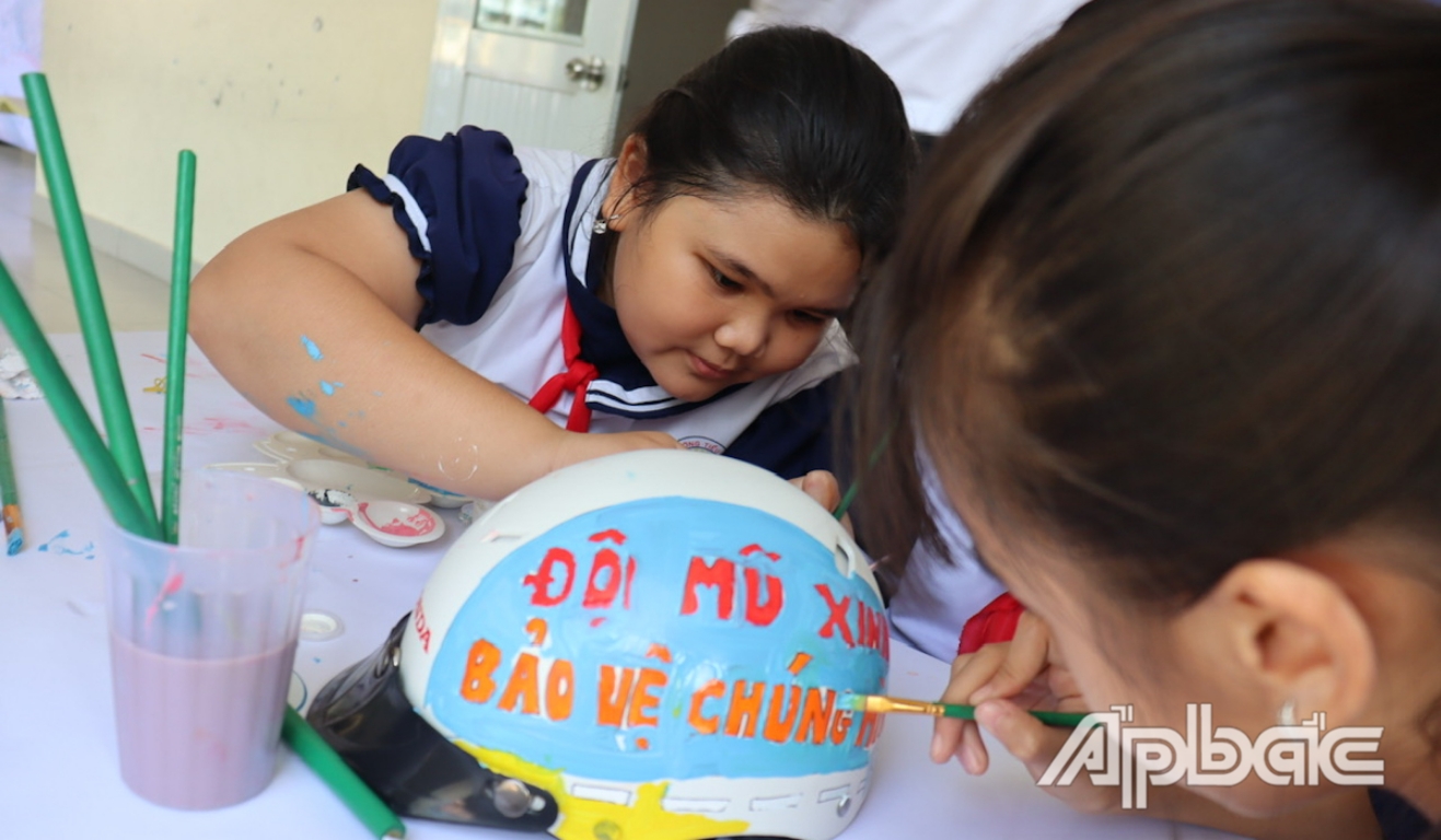 Các em học sinh tham gia phần thi vẽ lên mũ bảo hiểm.