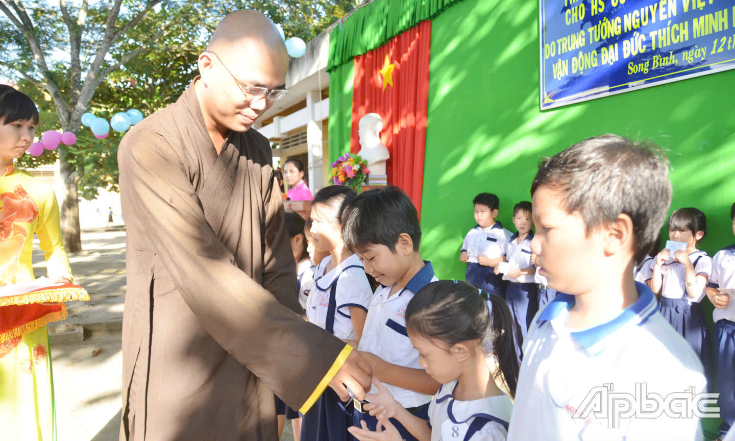 Đại đức Thích Minh Phước tặng thẻ bảo hiểm y tế cho học sinh có hoàn cảnh khó khăn của Trường Tiểu học Song Bình, huyện Chợ Gạo). Ảnh: Lê Hoài.