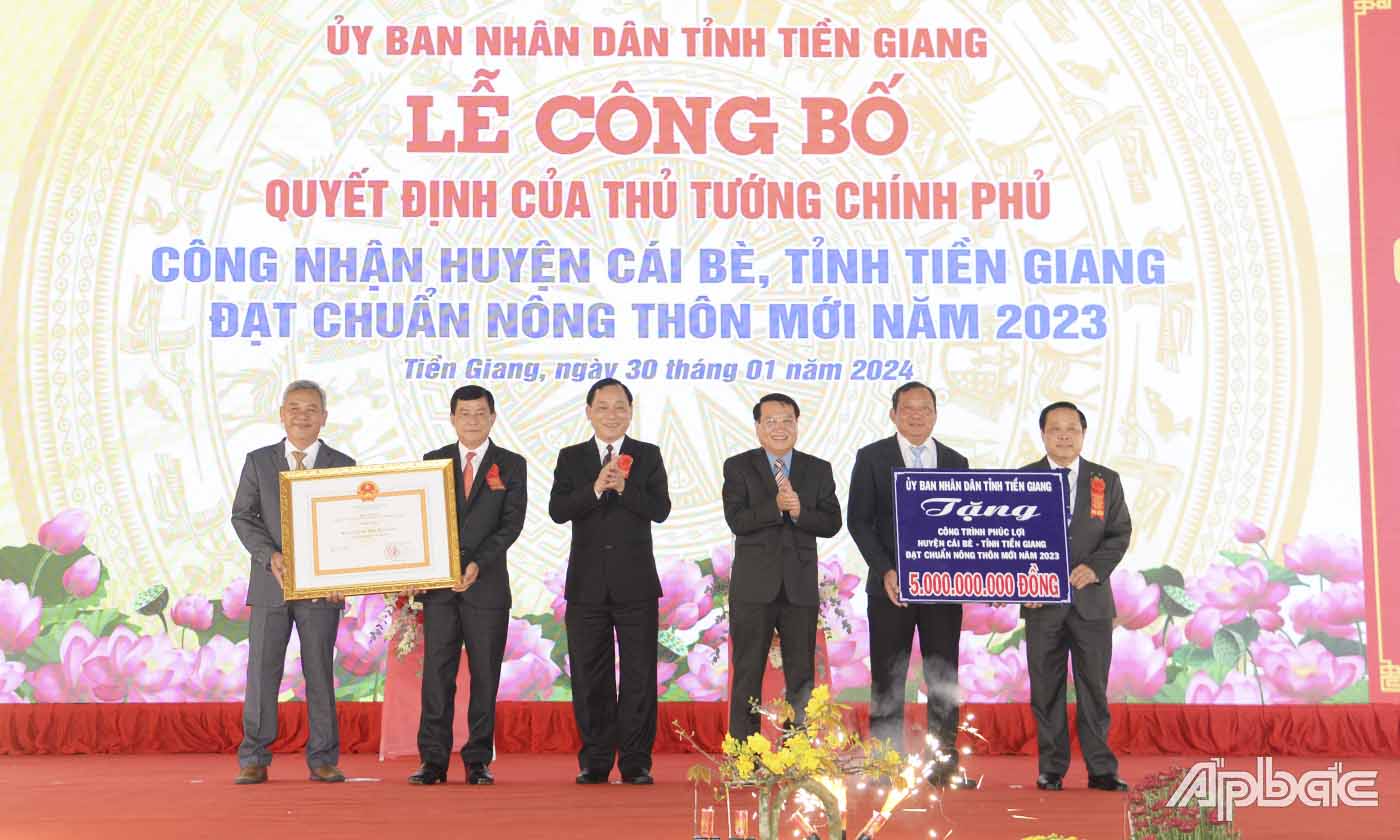 Cả nước có 302 đơn vị cấp huyện đạt chuẩn huyện Nông thôn mới. Trong ảnh: Đồng chí Nguyễn Văn Vĩnh (thứ 3 từ trái sang) và đồng chí Phạm Văn Trọng, Phó Chủ tịch UBND tỉnh (thứ 3 từ phải qua) trao Bằng công nhận của Thủ tướng Chính phủ và Bảng tượng trưng tặng công trình phúc lợi trị giá 5 tỷ đồng cho huyện Cái Bè, tỉnh Tiền Giang.