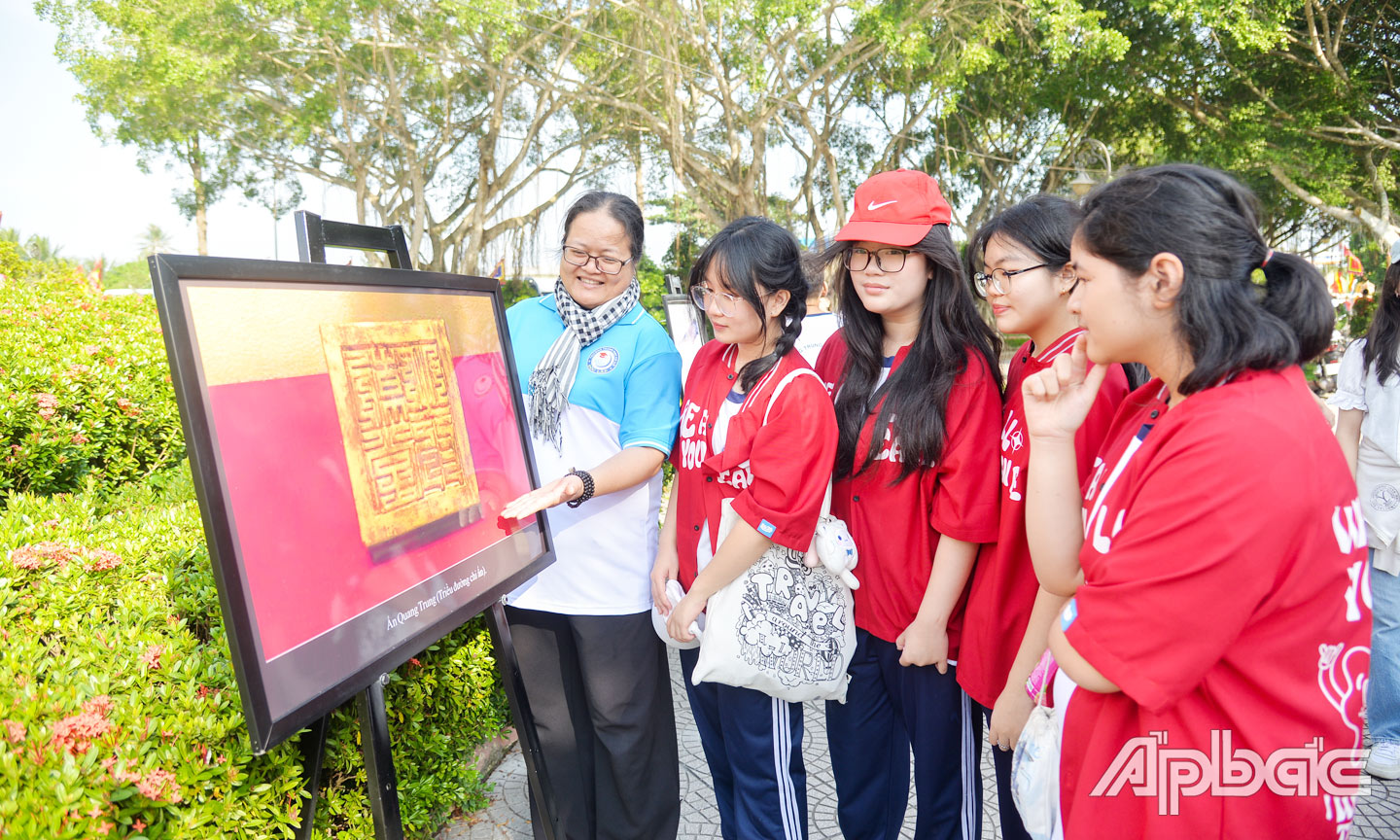 Du khách tham quan trưng bày, triển lãm hình ảnh về Chiến thắng Rạch Gầm - Xoài Mút và Anh hùng dân tộc Nguyễn Huệ tại khu di tích. Ảnh VĂN THẢO