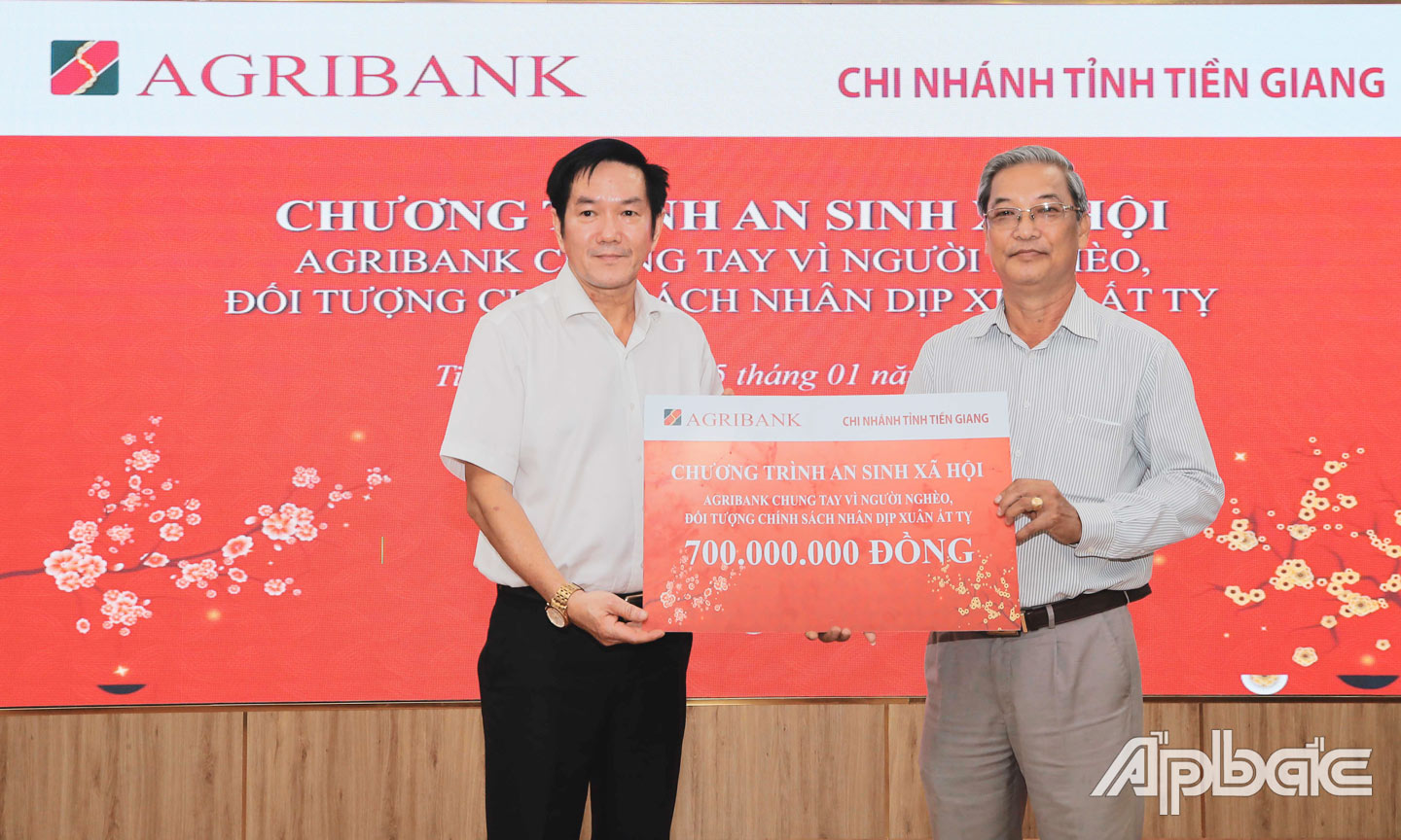 Bí thư Đảng ủy, Giám đốc Agribank chi nhánh tỉnh Tiền Giang Trương Văn Đoàn trao bảng tượng trưng số tiền hỗ trợ 700 triệu đồng cho ông Huỳnh Văn Hải, Phó Chủ tịch Ủy ban MTTQ Việt Nam tỉnh Tiền Giang.