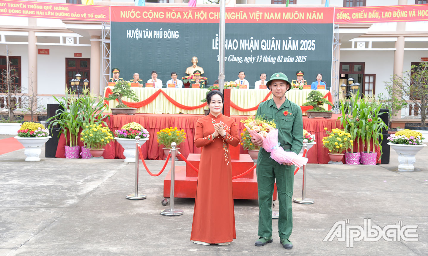 Đồng chí Nguyễn Hải Trâm tặng hoa cho tân binh Nguyễn Chí Linh đại diện 58 thanh niên huyện Tân Phú Đông lên đường nhập ngũ.