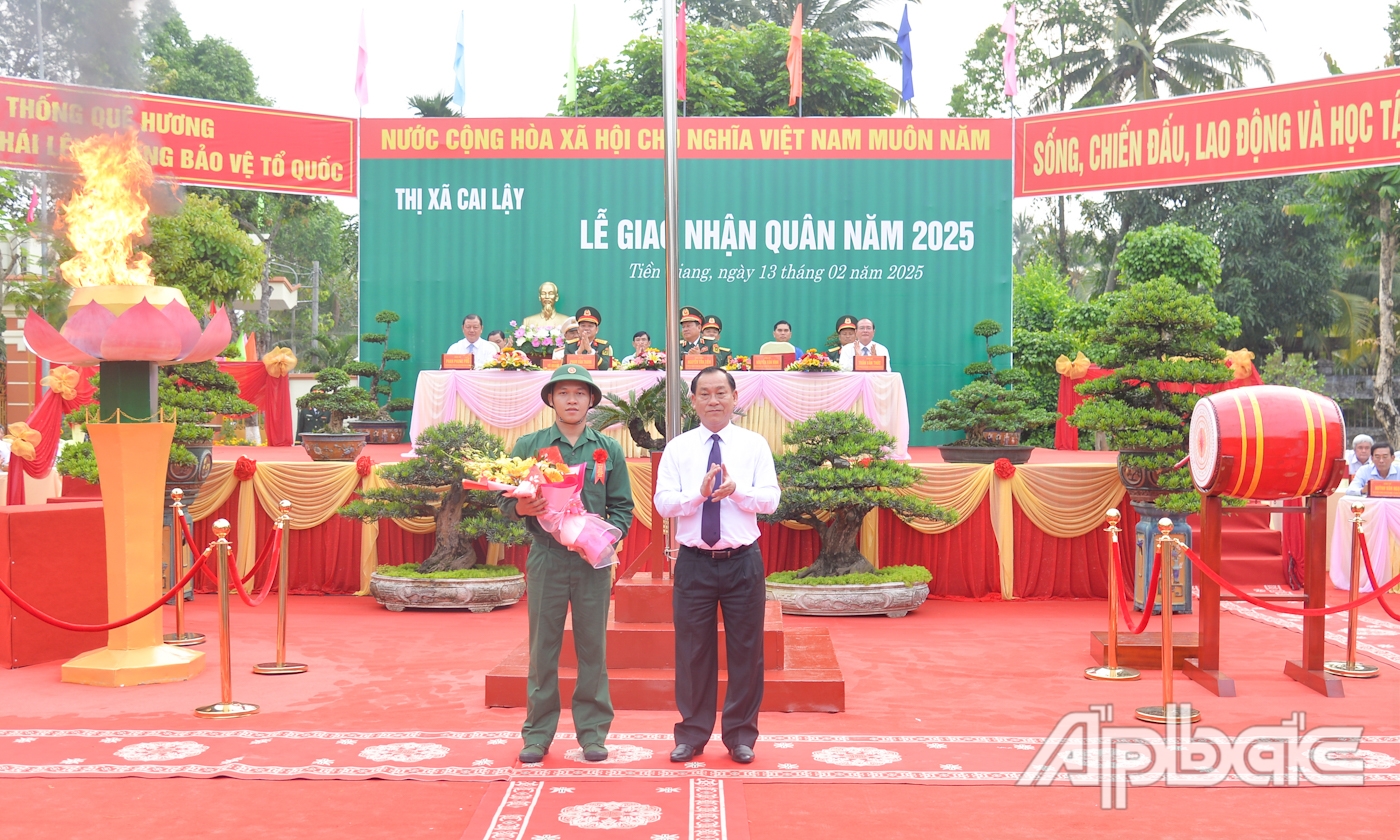 Đồng chí Nguyễn Văn Vĩnh tặng hoa cho tân binh Trương Anh Tuấn đại diện 129 thanh niên TX. Cai Lậy lên đường nhập ngũ.