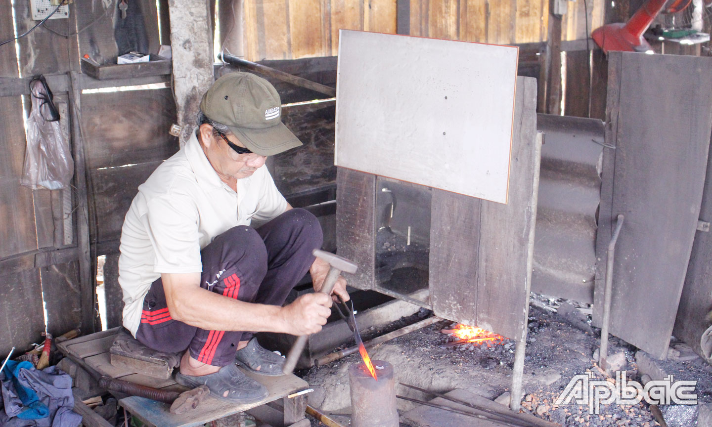 Ông Tám Hòa đang thực hiện các thao tác để làm ra một chiếc liềm. 