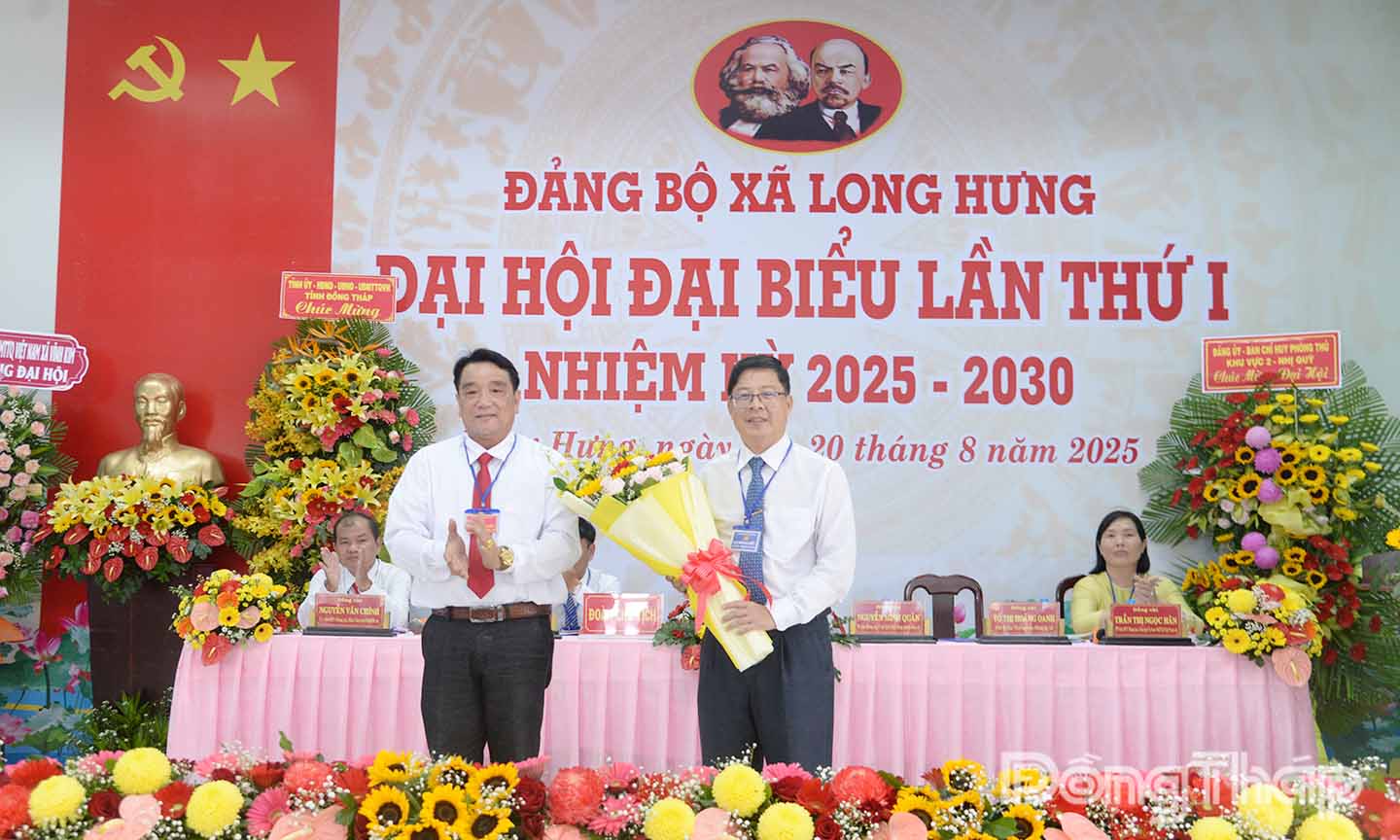 Đồng chí Nguyễn Minh Quân, Bí thư Đảng bộ xã Long Hưng (bên trái) tặng hoa cảm ơn đồng chí Trần Thanh Nguyên.